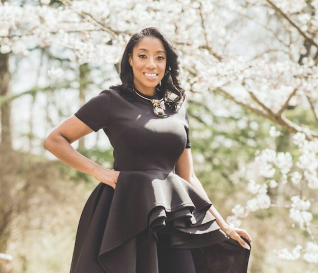 A woman in a black dress in front of cherry blossom trees